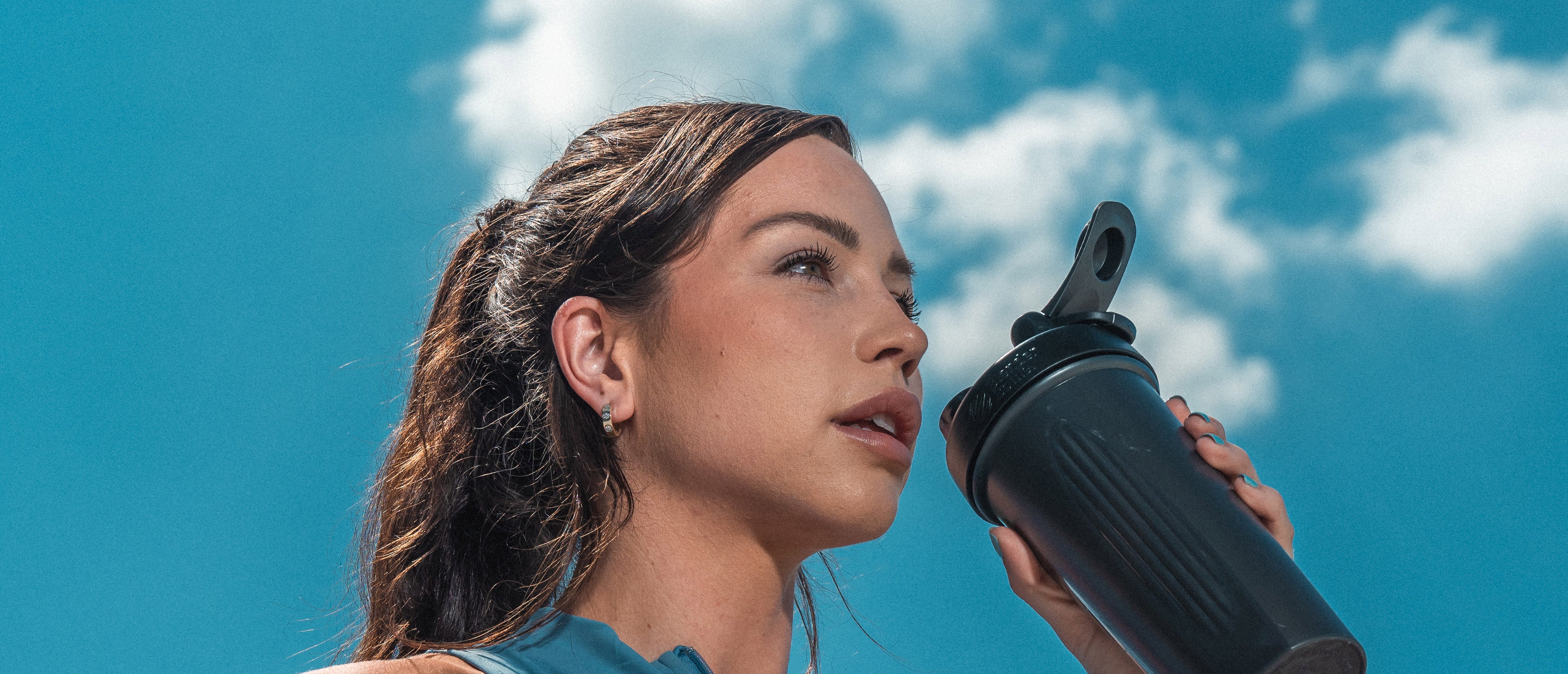 Woman drinking from shaker bottle.